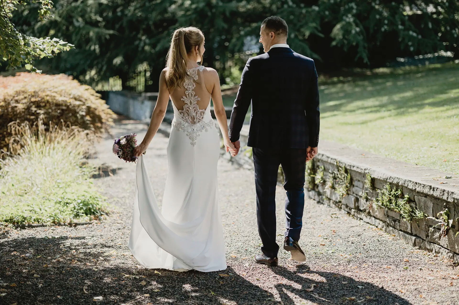 Brautpaar im Park der Villa St. Charles Hall Meggen mit eleganten Rückendetails am Brautkleid Hochzeitsfotografie Luzern Fotoatelier Mariano