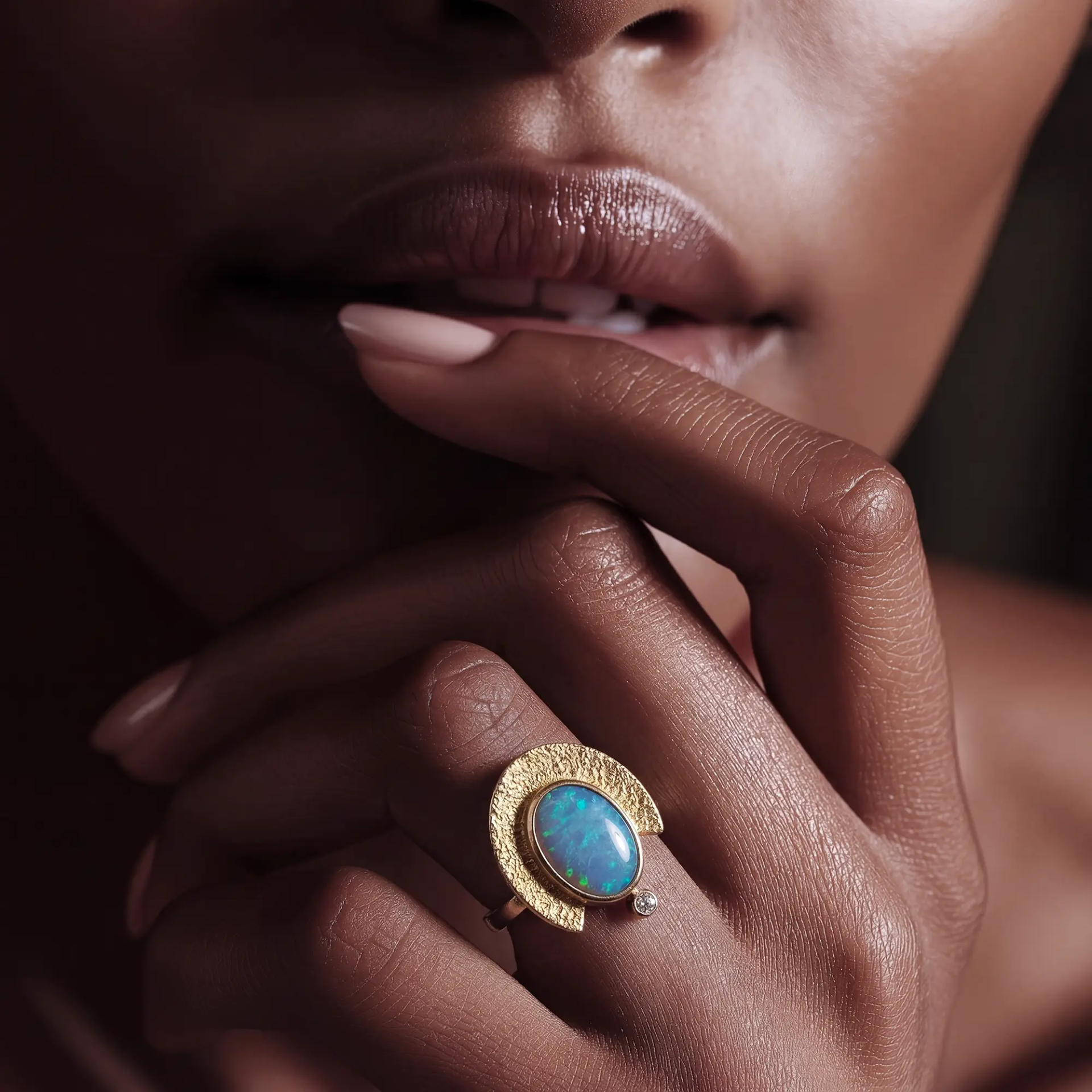 Goldring mit blauem Opal an einer Hand inszeniert in hochwertiger Schmuckfotografie mit exklusiver Lichtführung.