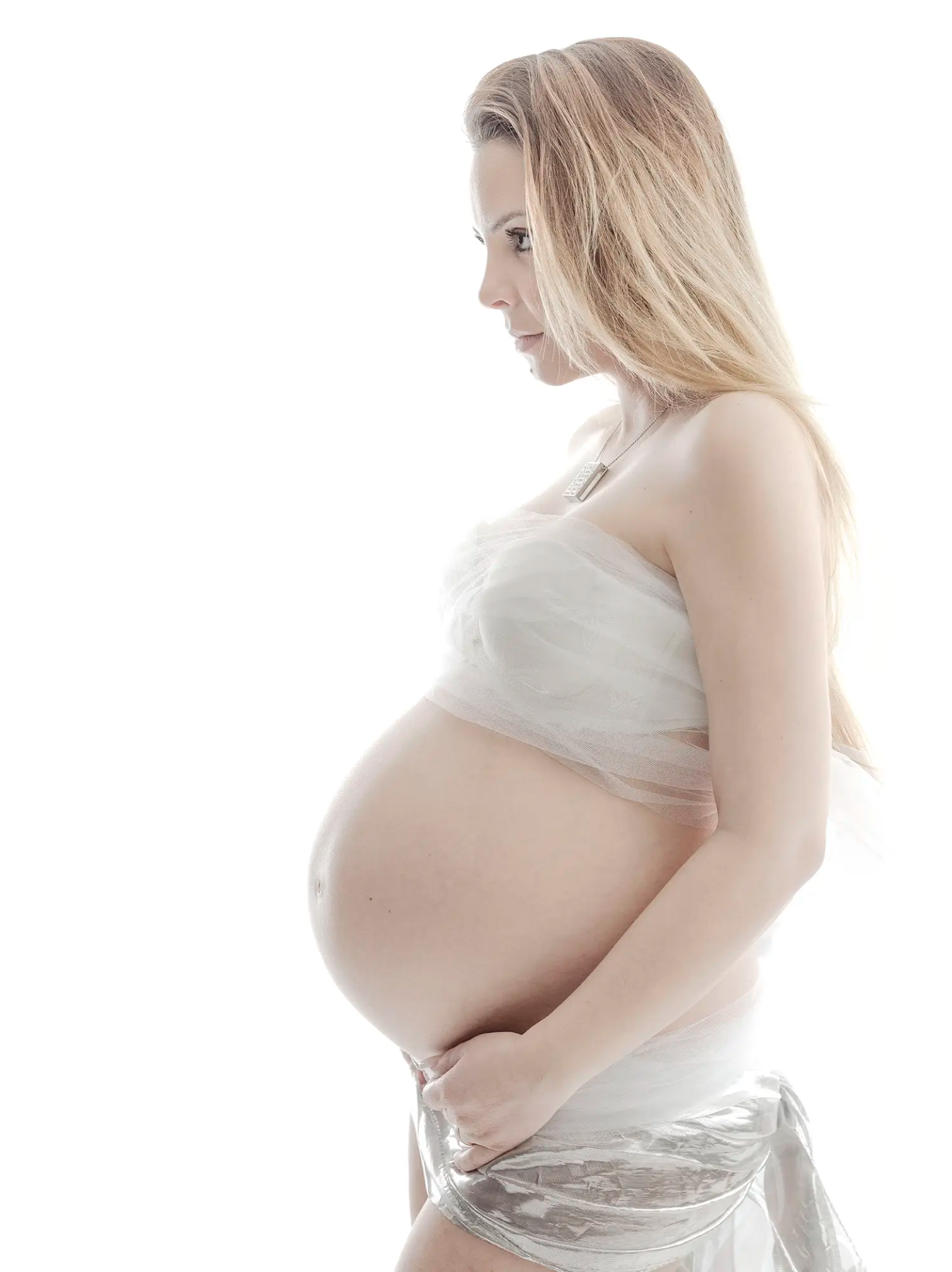 Babybauch-Fotoshooting in weißem Tuch vor hellem Studiohintergrund in Immensee