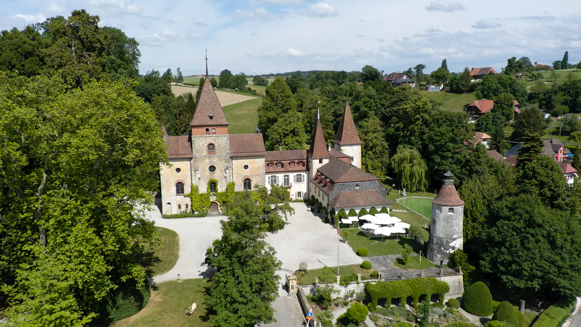 Drohnenaufnahme vom Schloss Münchenwiler mit Parkanlage und Innenhof als Hochzeitslocation bei Murten