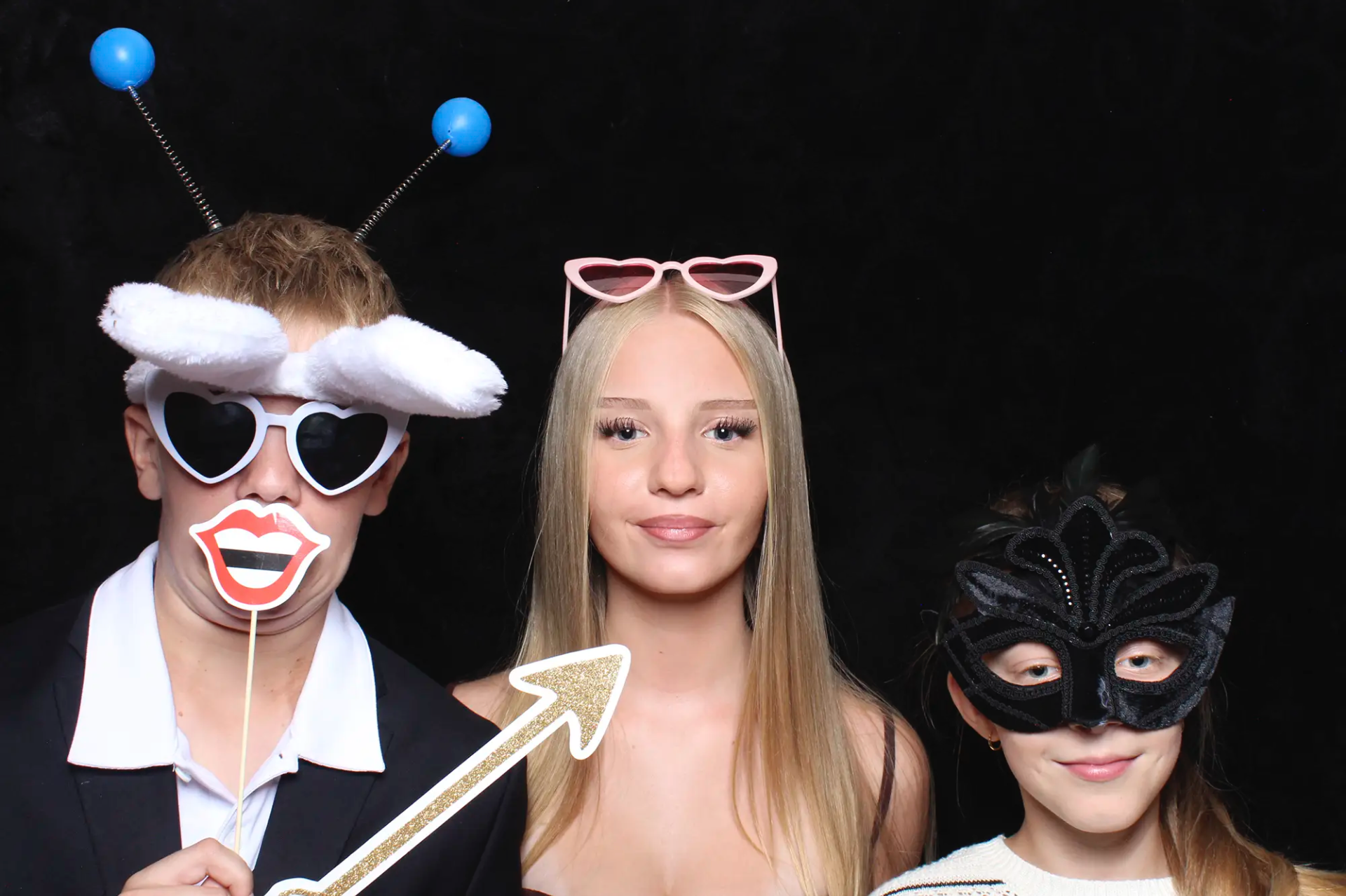 Hochzeitsgäste posieren mit lustigen Requisiten vor der Selfiebox im Heuboden Holzhäusern.