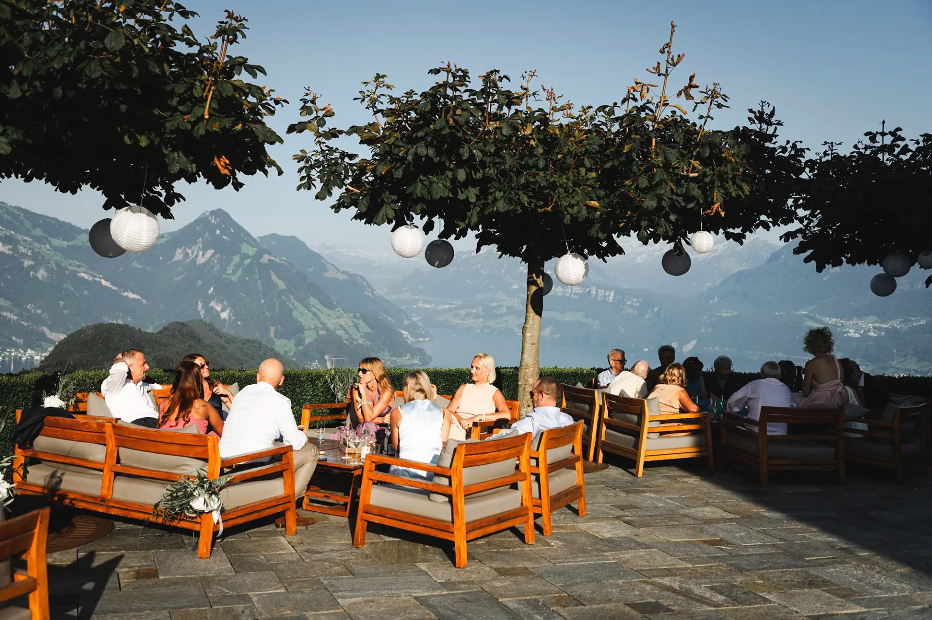 Gäste geniessen den Apéro auf der Terrasse der Villa Honegg mit Blick auf die Berge.