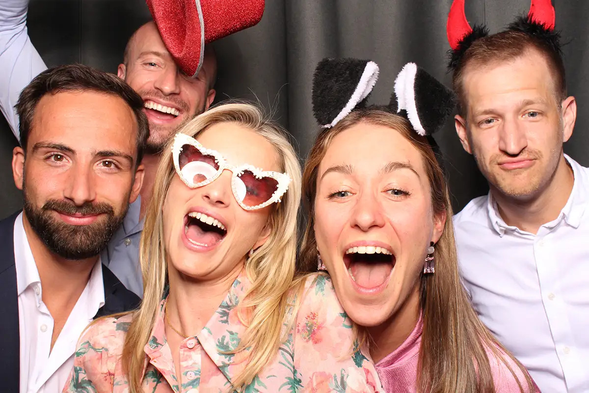 Gaeste lachen mit Party-Requisiten in der Selfiebox bei einer Hochzeit in Luzern