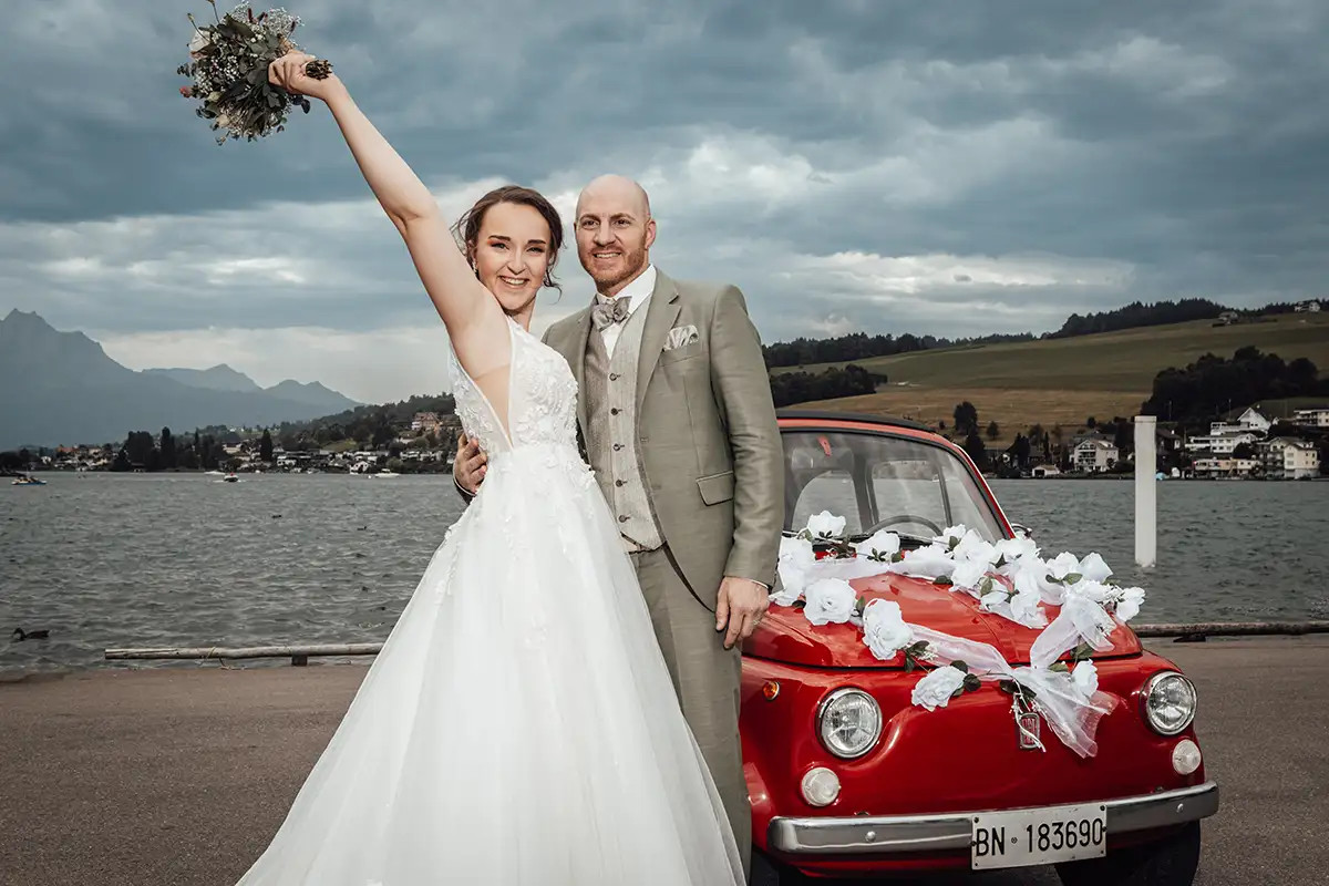 Braut Ramona mit Brautstrauss neben dem Oldtimer und Blick in die Zentralschweiz