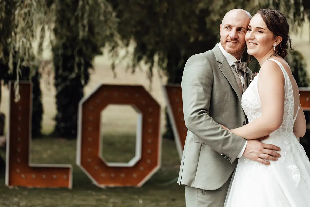 Ramona und Andrea vor dem Love Schriftzug bei ihrer Hochzeit im Hof Landschi