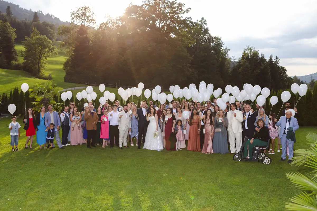 Hochzeitsgesellschaft von Luana und Luca beim Gruppenfoto mit weissen Ballonen in Kriens